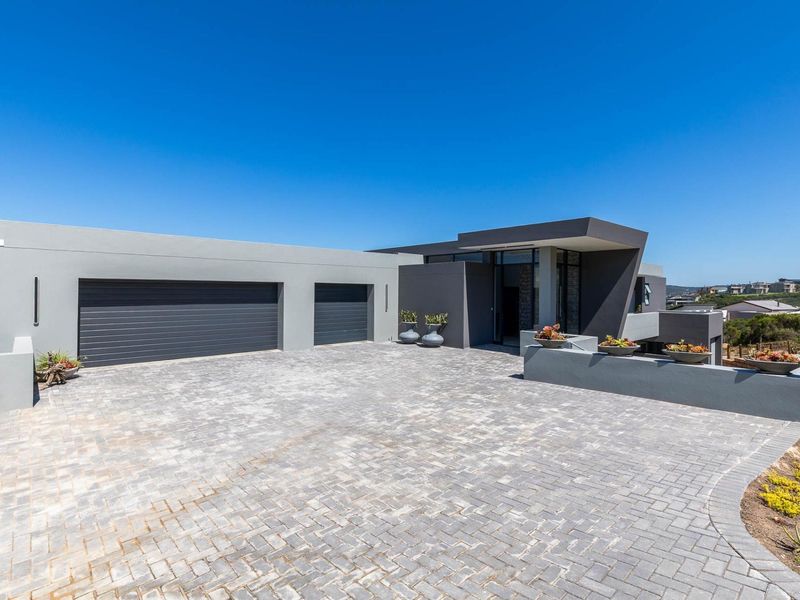 Modern architectural front elevation featuring a double garage, paved driveway, and clean contemporary lines with ocean views.