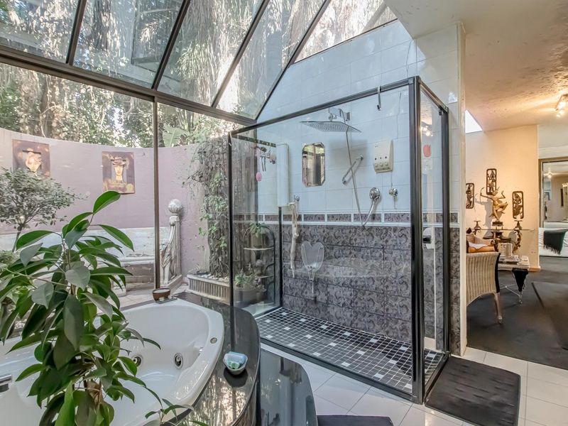 Unique bathroom featuring a glass roof, walk-in shower, and built-in bathtub, offering a bright and airy atmosphere with integrated garden views.