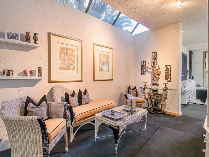 A cozy living area featuring textured walls, a large overhead skylight providing natural light, and built-in wall shelving.