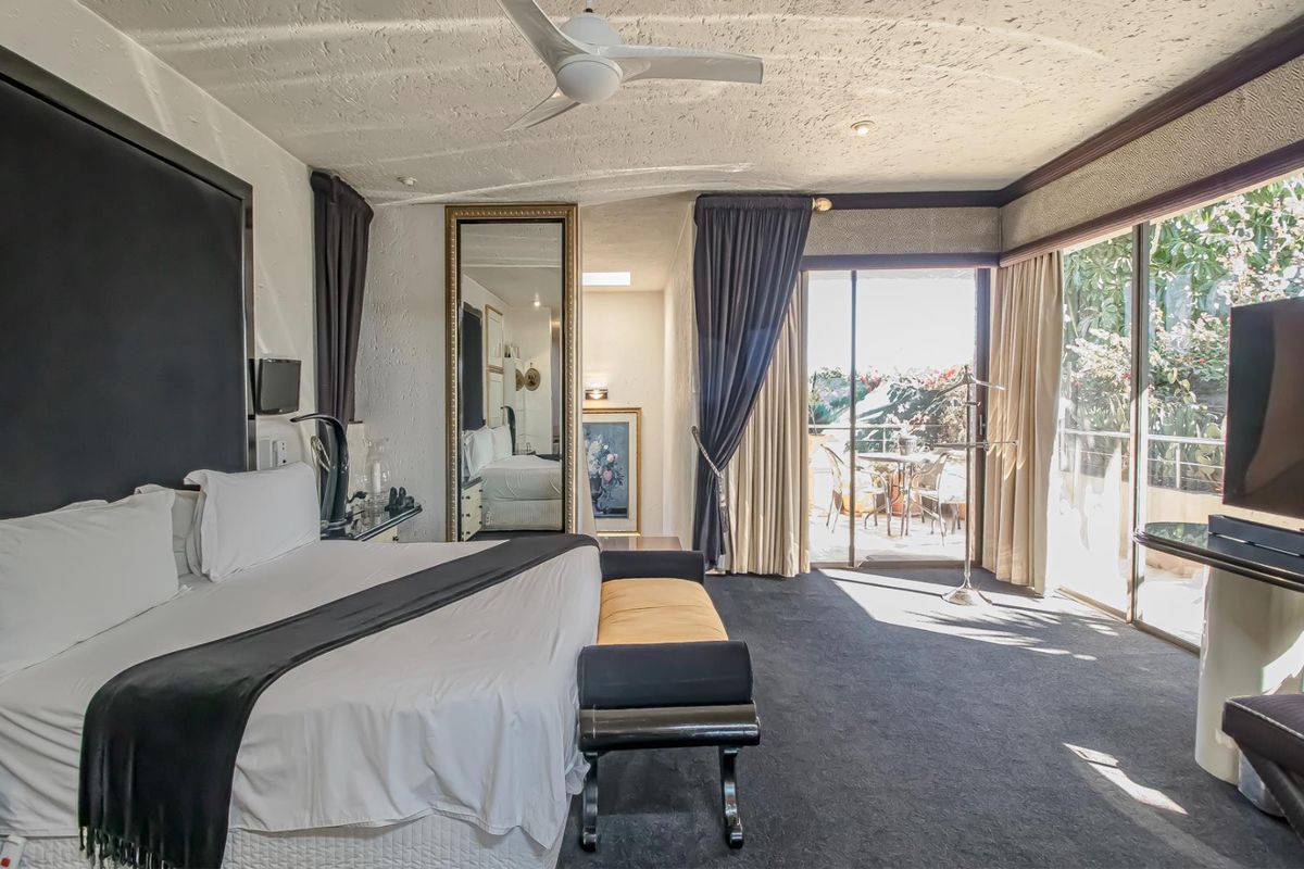 Spacious bedroom featuring a textured ceiling, ceiling fan, and large sliding glass doors providing direct access to an outdoor patio area.