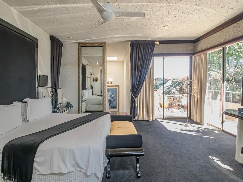 Spacious bedroom featuring a textured ceiling, ceiling fan, and large sliding glass doors providing direct access to an outdoor patio area.