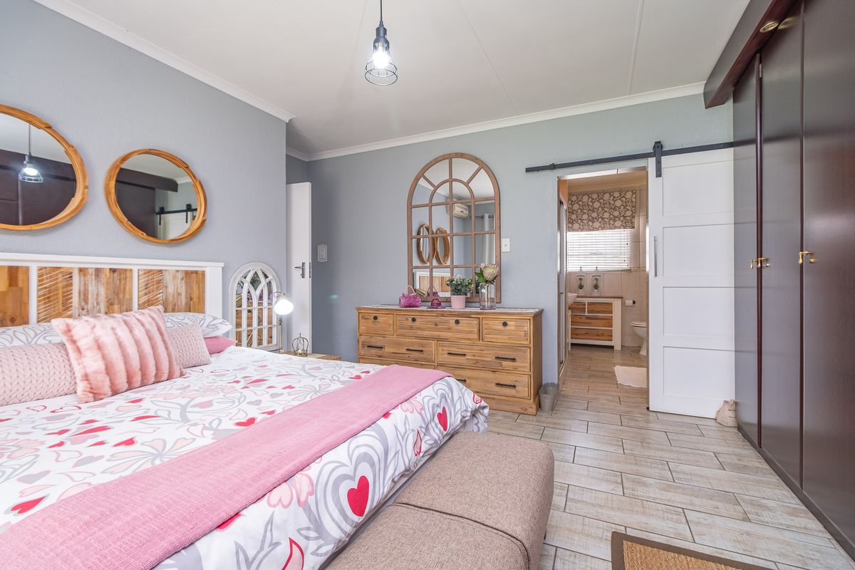 Spacious bedroom featuring tiled flooring, a built-in wardrobe, and a sliding barn door leading to an en-suite bathroom.
