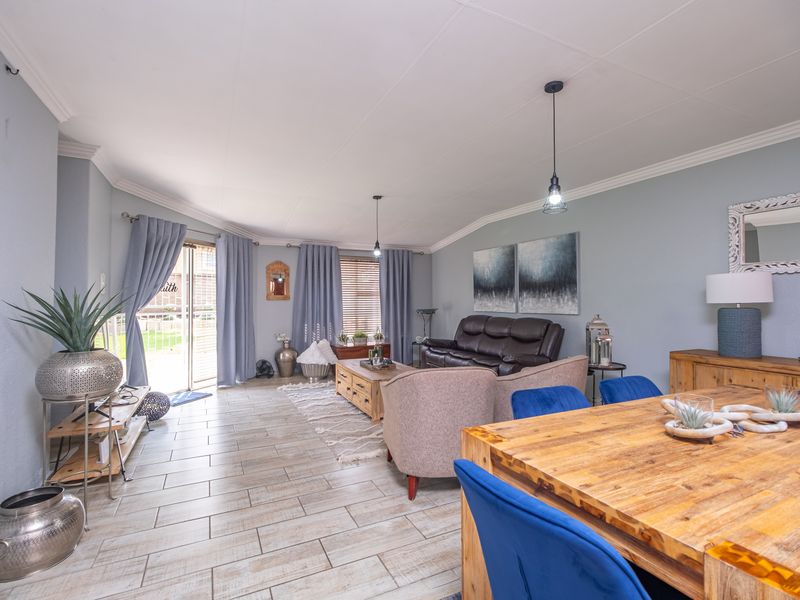 Spacious open-plan living and dining area featuring light-toned tiled flooring, neutral wall finishes, and a sliding glass door providing access to the exterior.