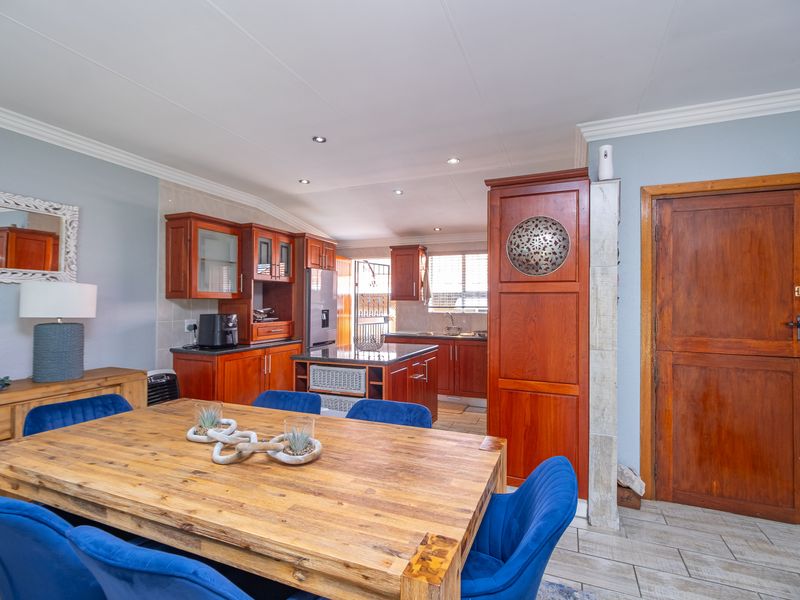 Open-plan kitchen and dining area featuring warm wooden cabinetry, granite countertops, tiled flooring, and recessed lighting, creating a functional and inviting living space.