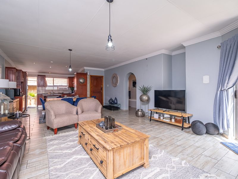 Spacious open-plan living and dining area featuring tiled flooring, an arched entryway, and direct access to an outdoor space through sliding glass doors.