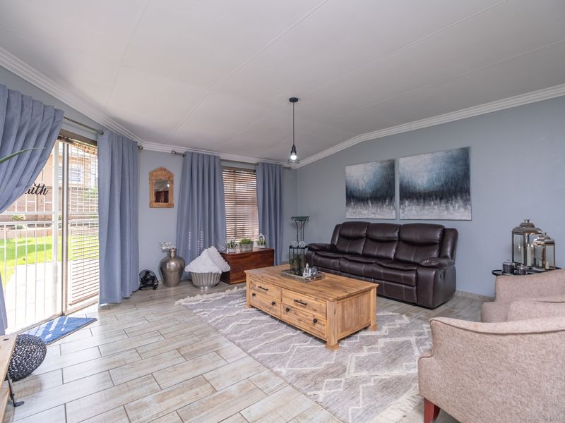 A well-maintained living room featuring tiled flooring, coved ceilings, and a sliding glass door providing direct access to the outdoor area.