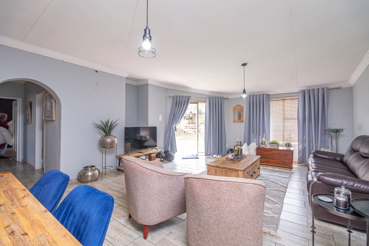 Spacious living room featuring tiled flooring, an arched entryway, and a sliding glass door providing access to the outdoor area.