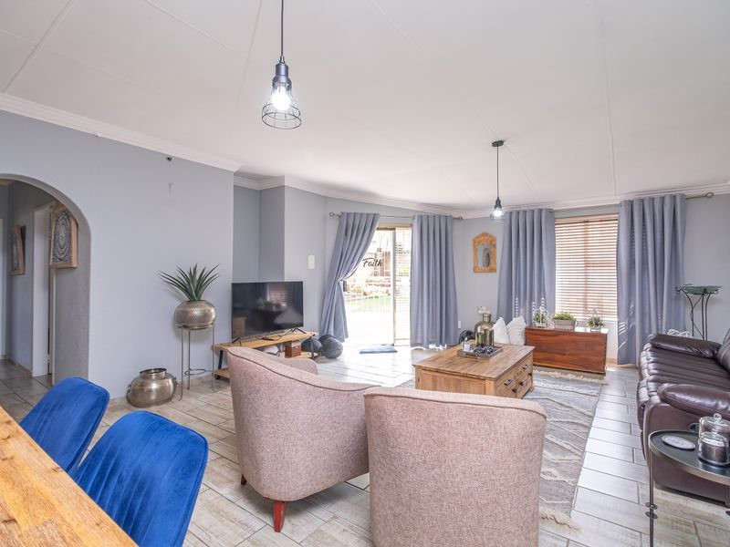 Spacious living room featuring tiled flooring, an arched entryway, and a sliding glass door providing access to the outdoor area.