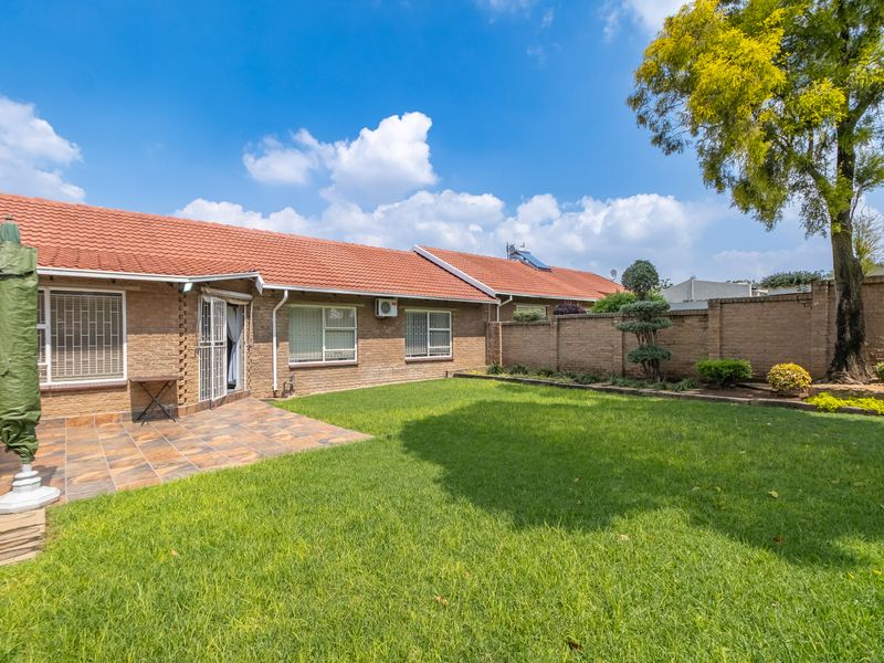 A well-maintained rear garden featuring a tiled patio area, brick boundary walls, and a lawn, providing a private outdoor space for the townhouse.