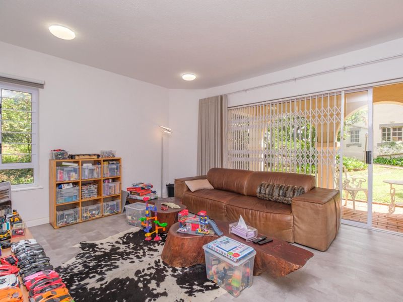 Spacious living room featuring modern laminate flooring, large sliding glass doors with security gate, and direct access to the outdoor patio area.