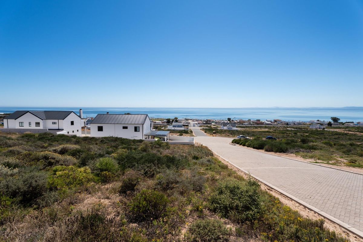 An elevated aerial view of a residential development featuring paved roads and coastal scenery with ocean views.