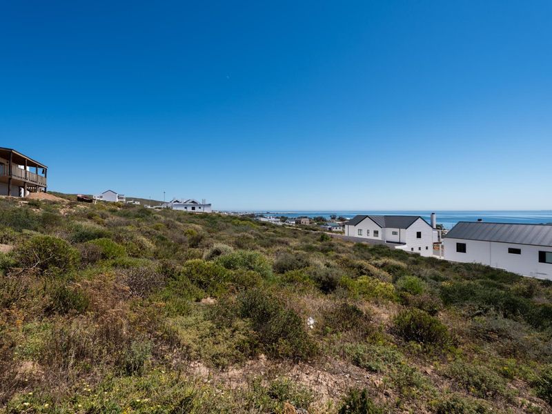 A scenic view of the coastal landscape and surrounding residential properties, showcasing the sloped terrain and proximity to the ocean.