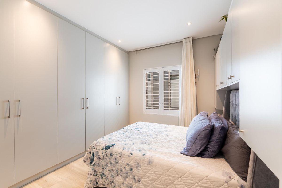 A well-maintained bedroom featuring extensive built-in cabinetry, plantation shutters, recessed lighting, and light-toned laminate flooring.