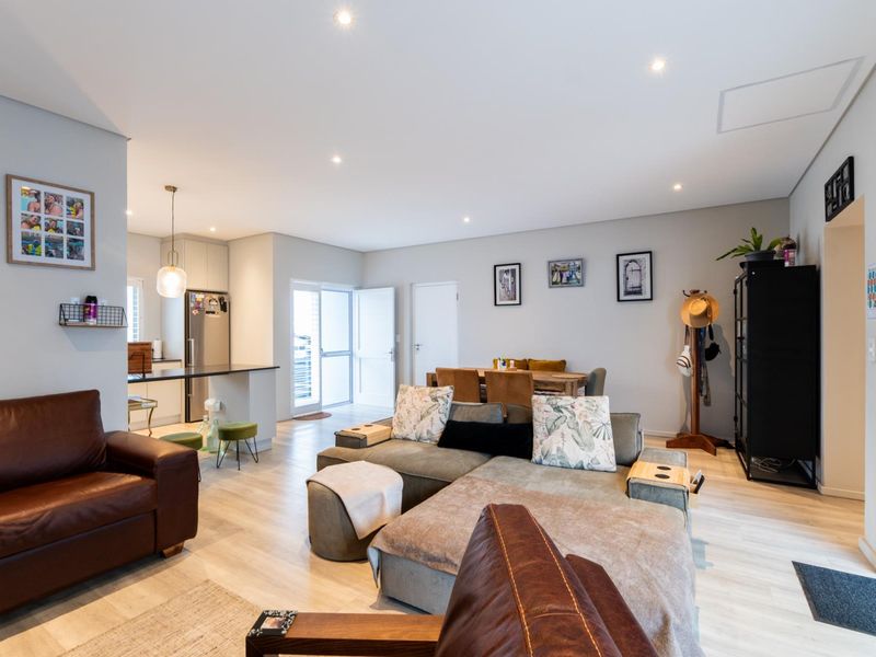 Spacious open-plan living and dining area featuring modern laminate flooring, recessed lighting, and a sleek kitchen with stone countertops.