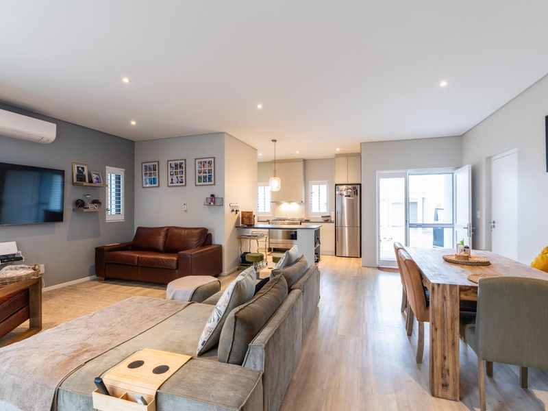 Spacious open-plan living, dining, and kitchen area featuring modern laminate flooring, recessed lighting, and a well-appointed kitchen with integrated appliances.