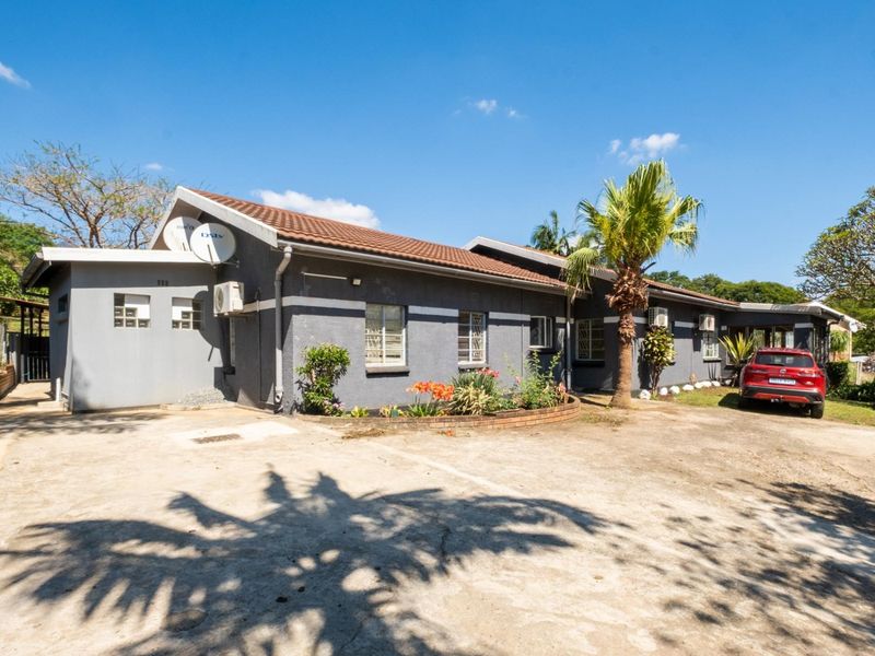 Front exterior view of a single-story house featuring a concrete driveway, tiled roof, and established garden beds.