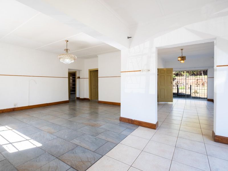 Spacious open-plan living area featuring tiled flooring, neutral walls, and direct access to the outdoor space through a sliding glass door.
