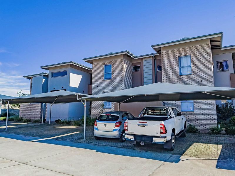 Front elevation of a modern apartment complex featuring brick facade finishes and dedicated covered parking bays with shade cloth structures.