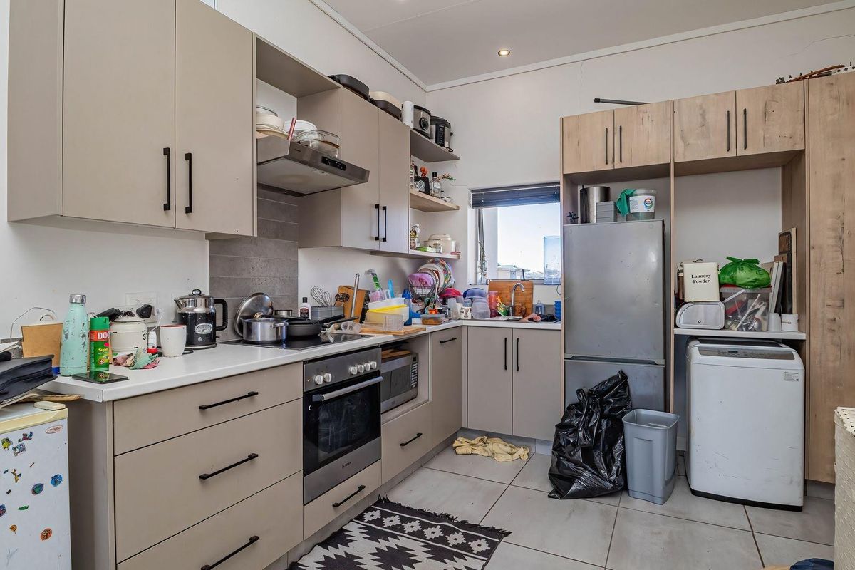 A functional kitchen featuring modern cabinetry, built-in oven, electric hob, and tiled flooring, offering a practical layout for daily cooking and utility needs.