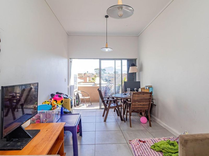 A functional living area featuring tiled flooring and a sliding glass door that provides access to an outdoor balcony.