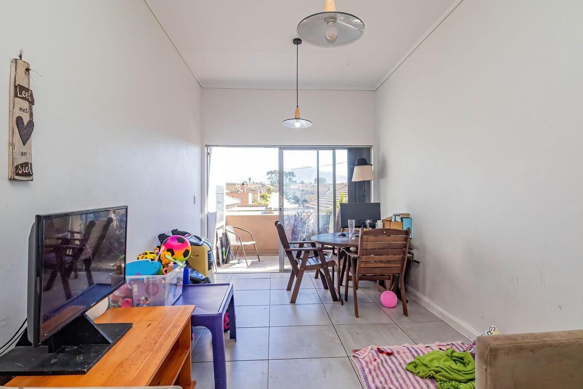 A functional living area featuring tiled flooring and a sliding glass door that provides access to an outdoor balcony.