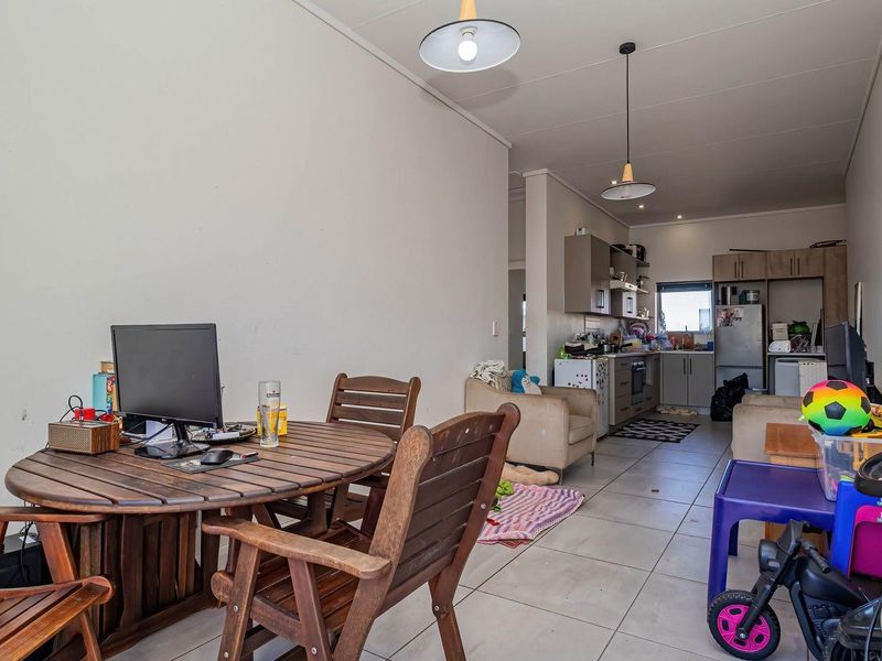 Open-plan living and kitchen area featuring tiled flooring, modern cabinetry, and pendant lighting, offering a functional layout for daily living.