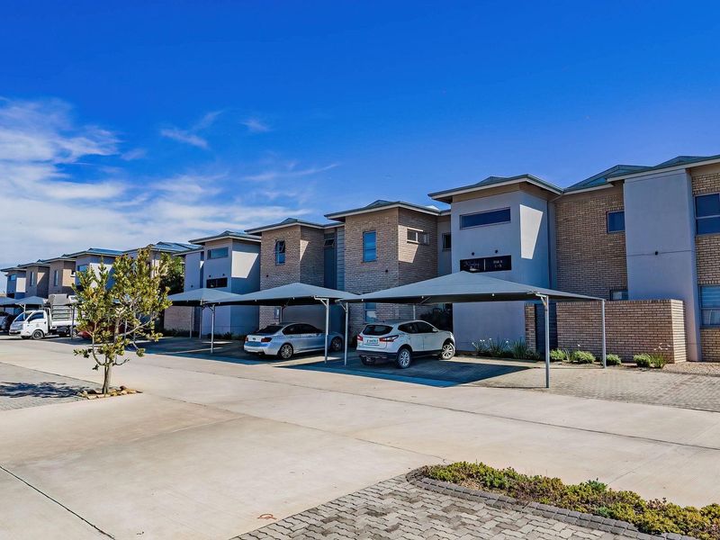 A view of the apartment complex exterior featuring a paved driveway and multiple covered parking bays.