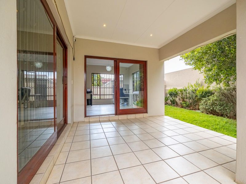 A clean, covered patio area featuring tiled flooring and recessed lighting, providing seamless access to the interior through large sliding glass doors.