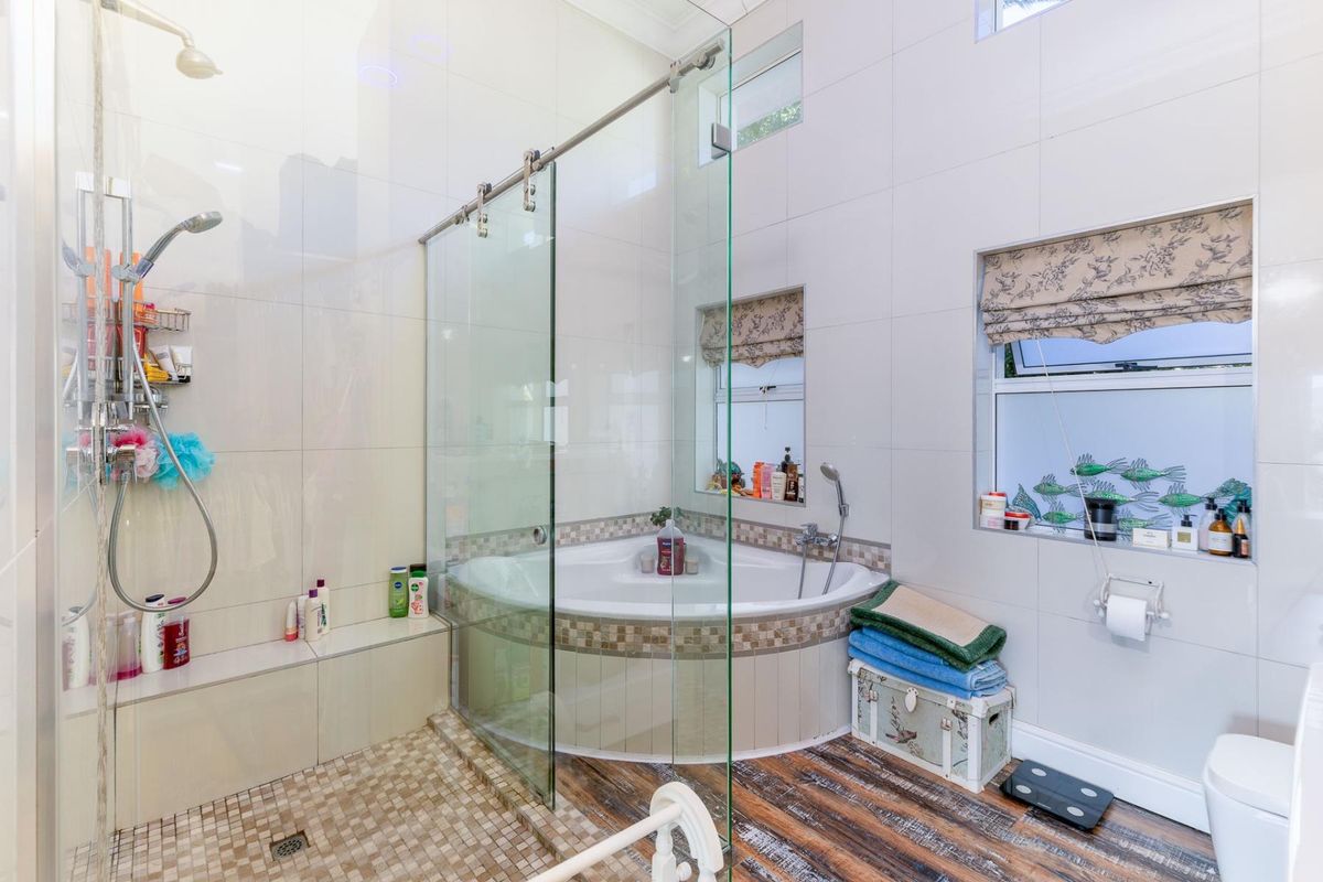 Modern bathroom featuring a corner bathtub, a spacious glass-enclosed shower with a built-in bench, and contemporary tiled finishes throughout.
