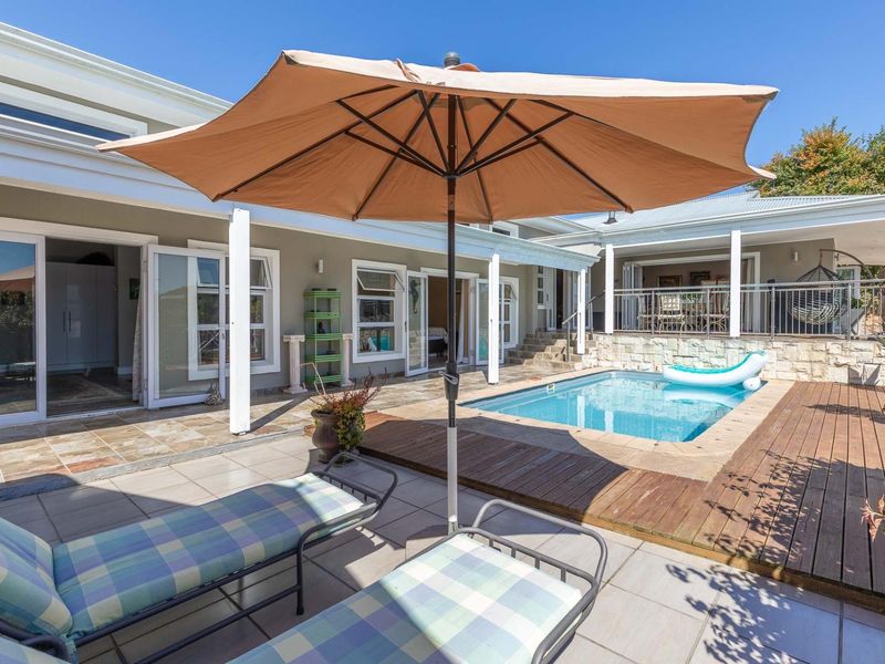 Outdoor entertainment area featuring a swimming pool, timber decking, and tiled patio, seamlessly connected to the home via multiple sliding glass doors.