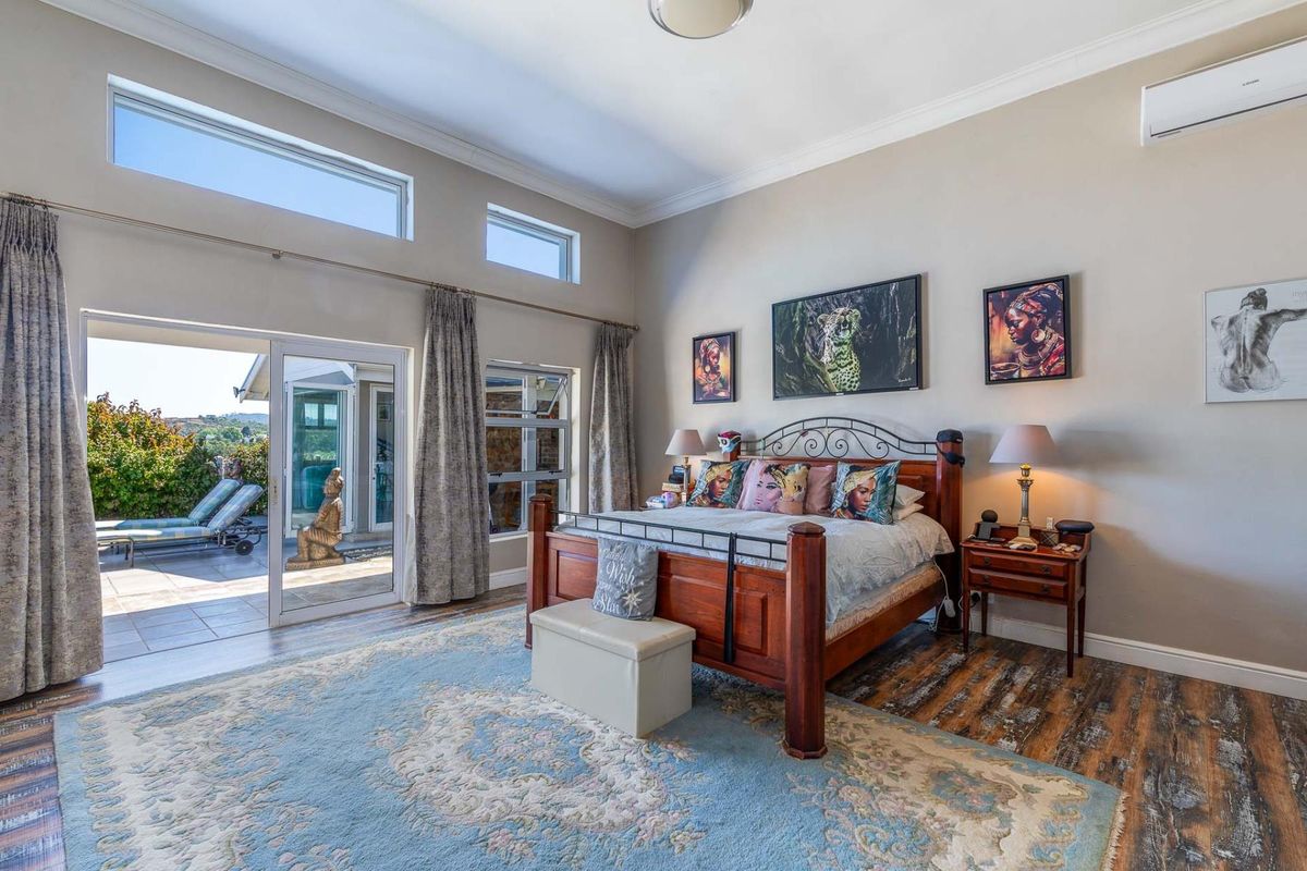 Spacious bedroom featuring high ceilings, clerestory windows, split-system air conditioning, and direct access to an outdoor patio through sliding glass doors.