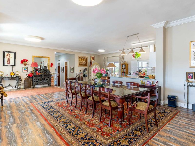 Spacious open-plan dining and kitchen area featuring wood-look laminate flooring, a breakfast bar, and integrated kitchen cabinetry with modern lighting fixtures.