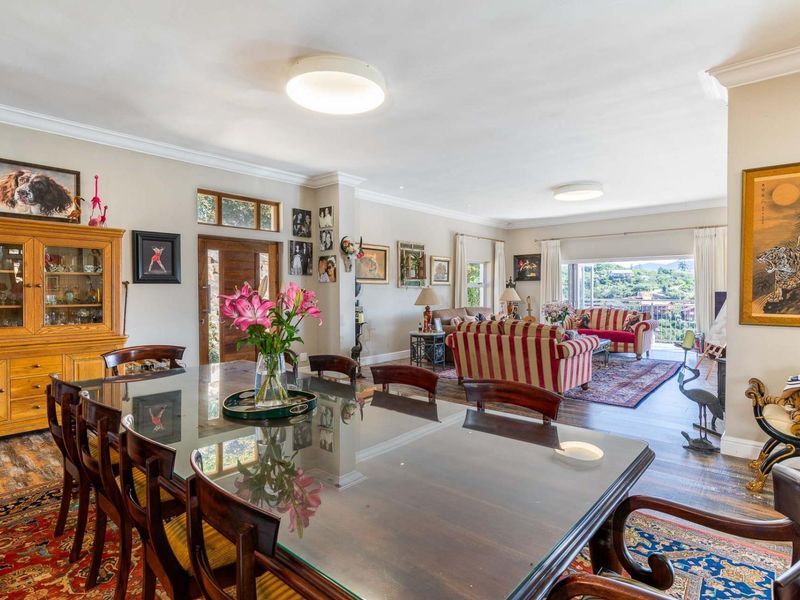 Spacious open-plan living and dining area featuring warm wooden flooring, coved cornicing, and large sliding doors that open to an outdoor balcony.