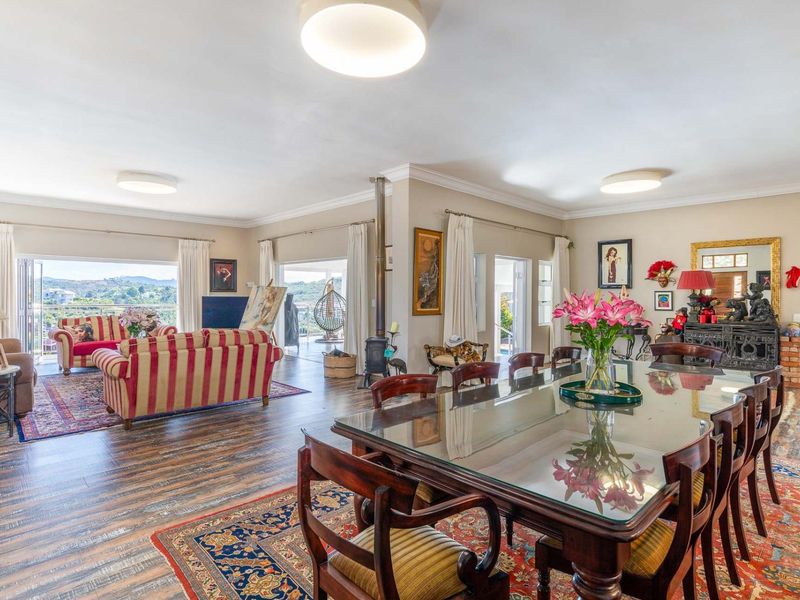 Spacious open-plan living and dining area featuring wood-look flooring, a central wood-burning fireplace, and large sliding doors opening to a scenic outdoor view.