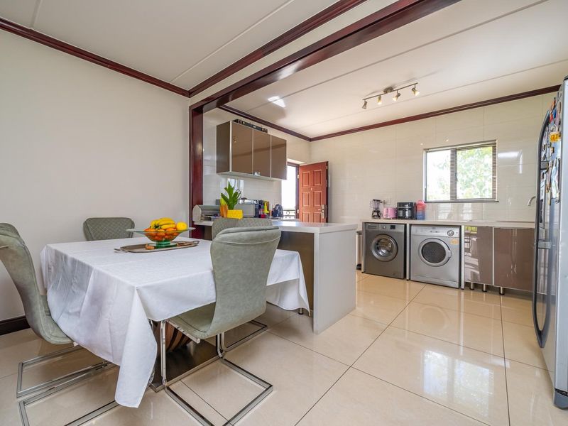 Open-plan kitchen and dining area featuring tiled flooring, modern cabinetry, a central island, and integrated laundry facilities.