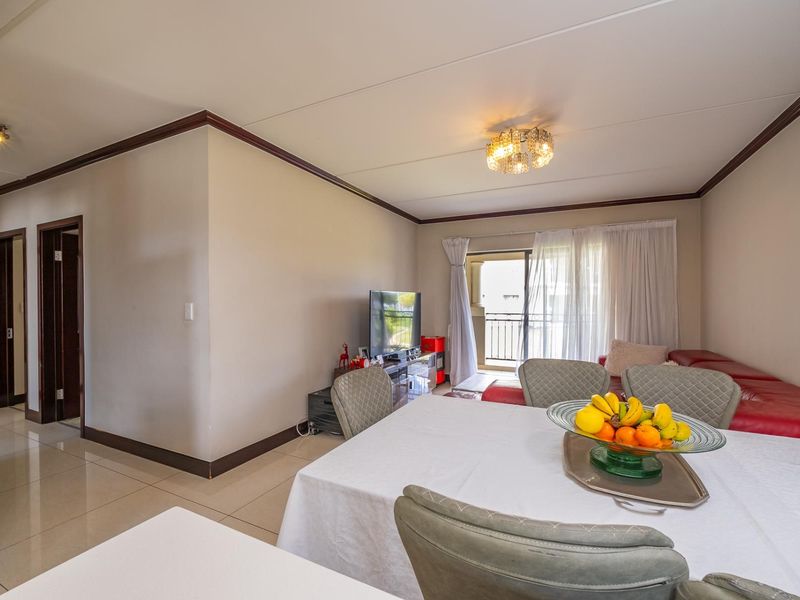 Open plan living and dining area featuring tiled floors, neutral walls, and a sliding glass door leading to a balcony.