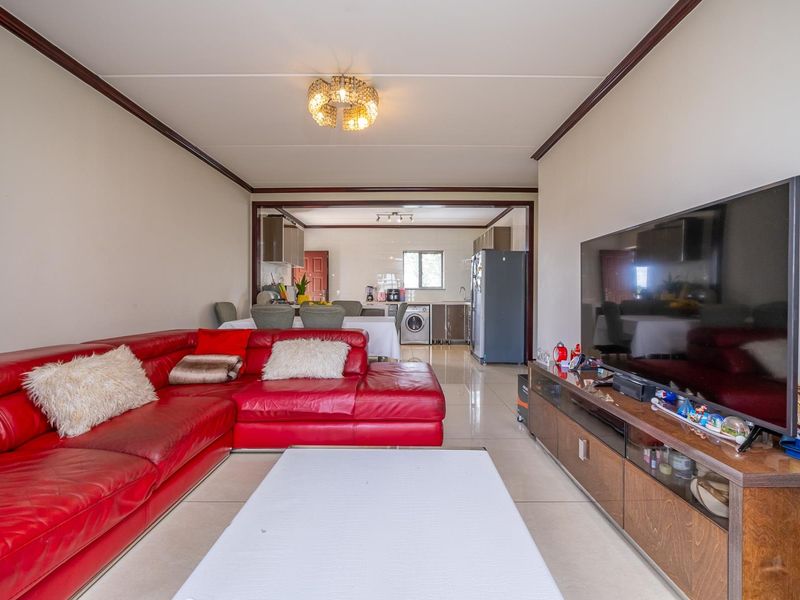 Open plan living and kitchen area featuring tiled flooring, ceiling molding, and a functional kitchen layout with integrated laundry space.