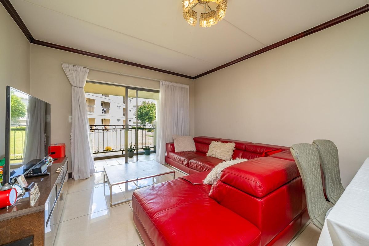 A bright living room featuring tiled flooring and a sliding glass door that provides direct access to a private balcony.