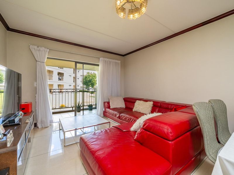 A bright living room featuring tiled flooring and a sliding glass door that provides direct access to a private balcony.