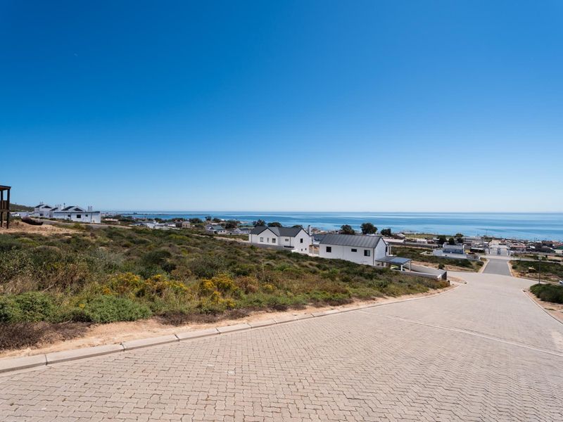 A scenic view overlooking a coastal residential area with a paved road leading towards the ocean.