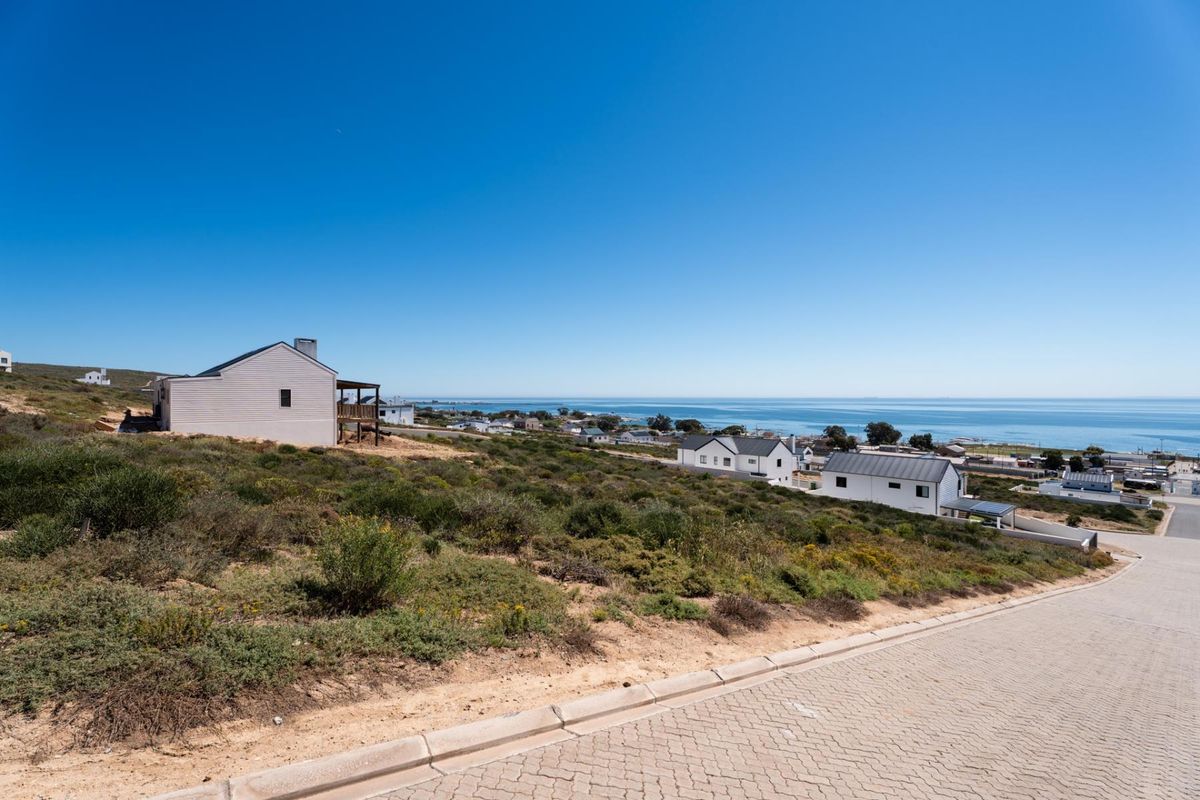 A scenic elevated view of the coastal residential area and ocean from a paved street.