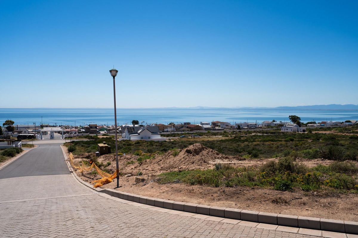 A scenic view overlooking a coastal residential area with a paved driveway and street infrastructure in the foreground.