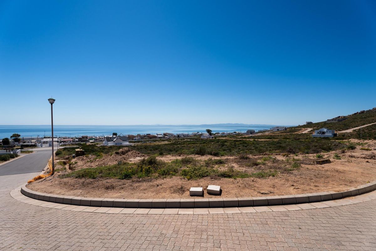 A vacant residential plot featuring a paved driveway, concrete curbing, and expansive coastal views over the surrounding neighborhood.
