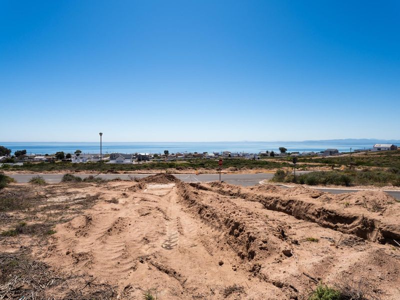 A wide-angle view of a vacant residential plot overlooking the coastline and ocean, showcasing the potential for a scenic coastal home build.