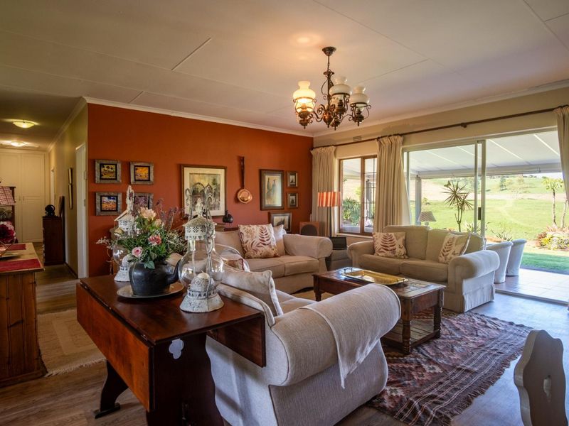 A comfortable living room featuring laminate flooring, a classic chandelier, and large sliding glass doors that provide natural light and access to the patio.