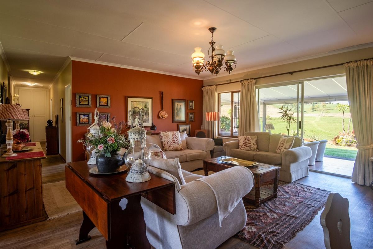 A comfortable living room featuring laminate flooring, a classic chandelier, and large sliding glass doors that provide natural light and access to the patio.