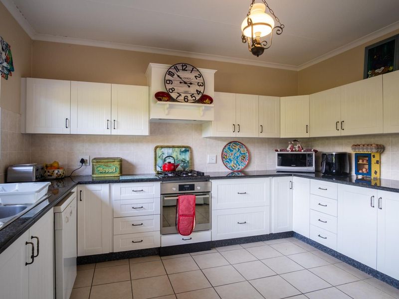A functional kitchen featuring white cabinetry, granite countertops, a gas hob, built-in oven, and tiled flooring with a neutral backsplash.