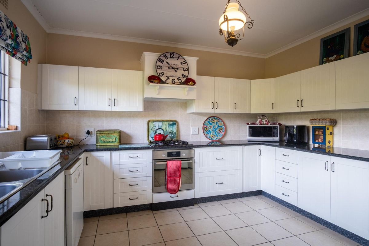 A functional kitchen featuring white cabinetry, granite countertops, a gas hob, built-in oven, and tiled flooring with a neutral backsplash.