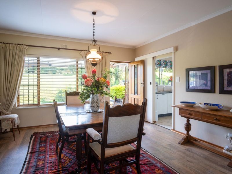 A well-lit dining room featuring laminate flooring, a sliding door leading to the exterior, and a classic pendant light fixture.