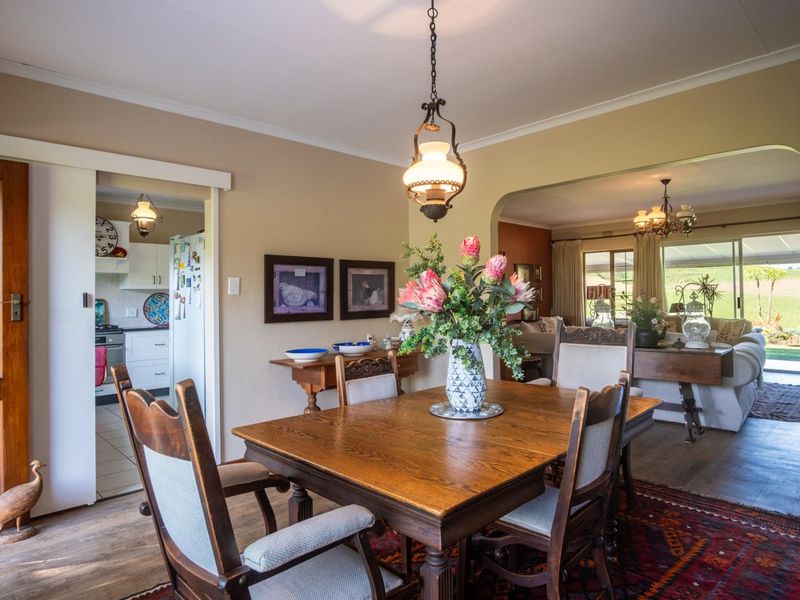 A traditional dining room featuring a wooden dining set, pendant lighting, and an open-plan layout connecting to the kitchen and living area.